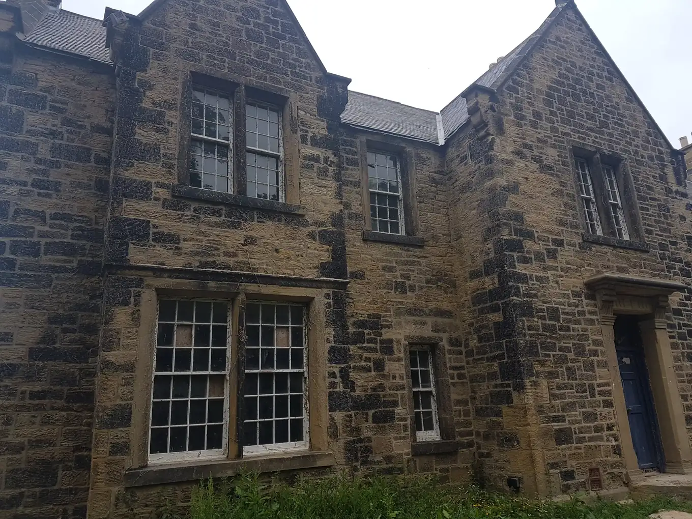 Weathered sandstone house before shot blasting in Durham-style stone cleaning