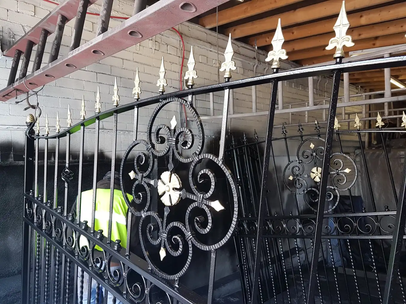 Iron gates painted black with gold finials after blasting