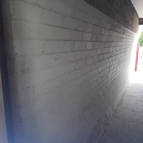 Painted brick alley wall before blasting