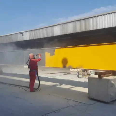 Operative shot blasting yellow steel beam