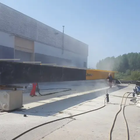 Steel beams being blasted outdoors